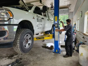 A white pickup truck on a lift getting worked on by GMK Mechanical in Gap, PA